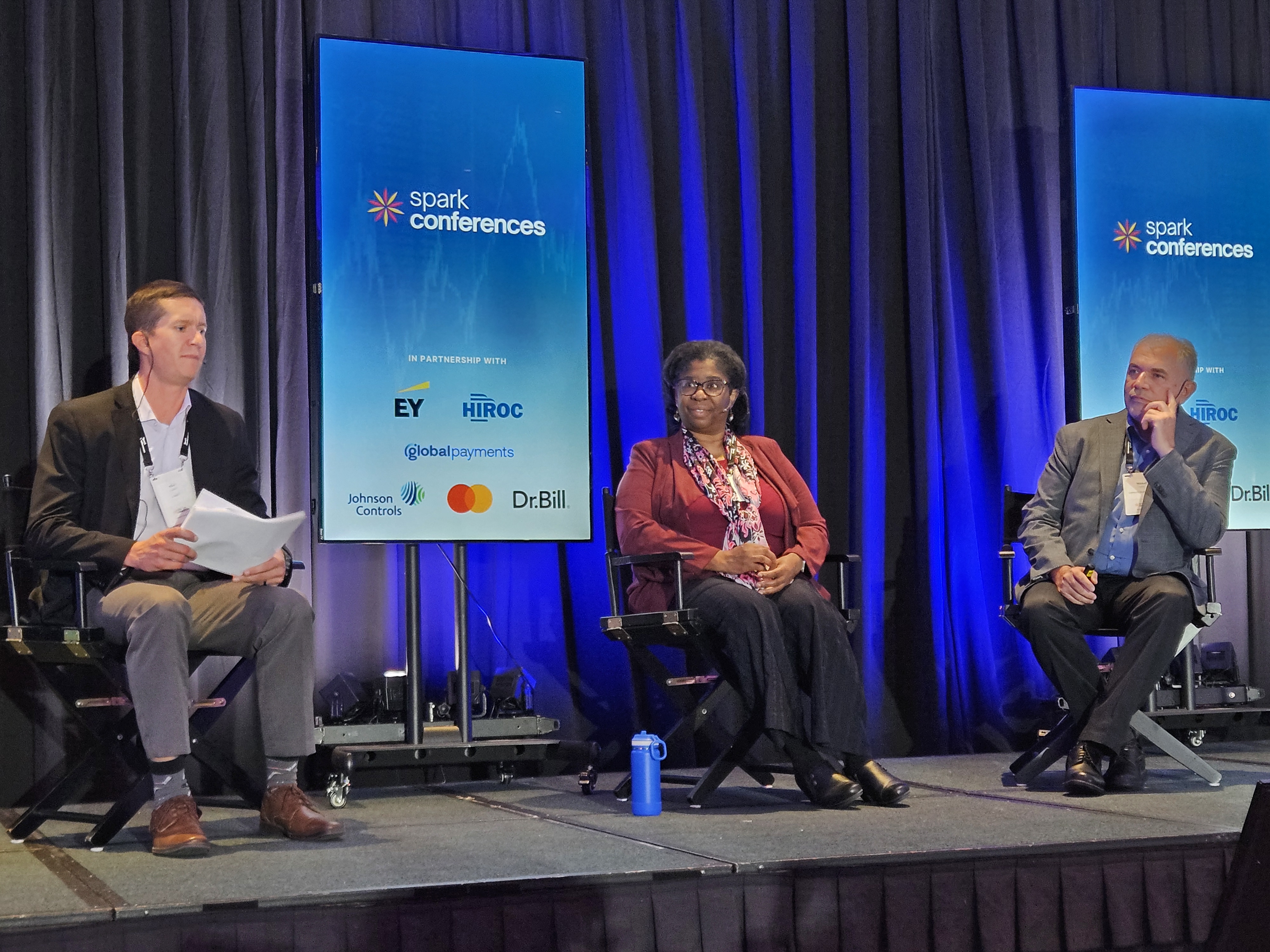 Three speakers sit on stage during their fireside chat session.