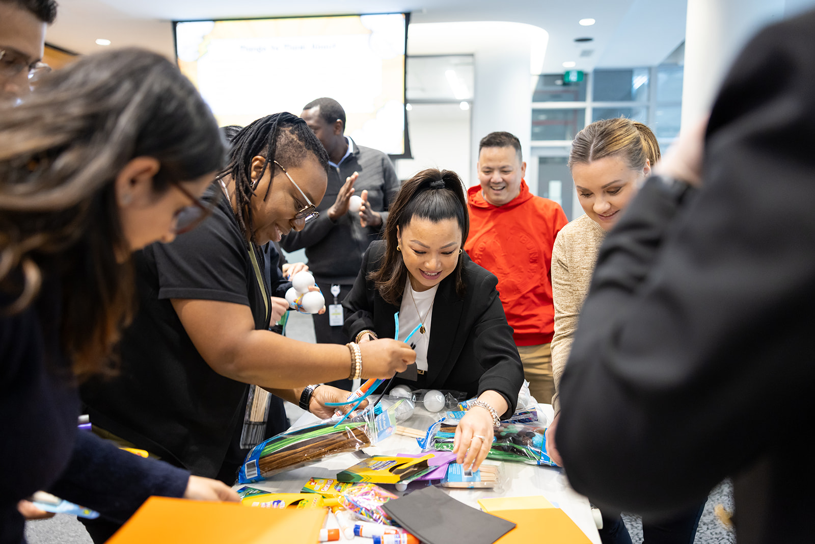 Staff reach for arts and crafts supplies on a table at the HIROC cafe