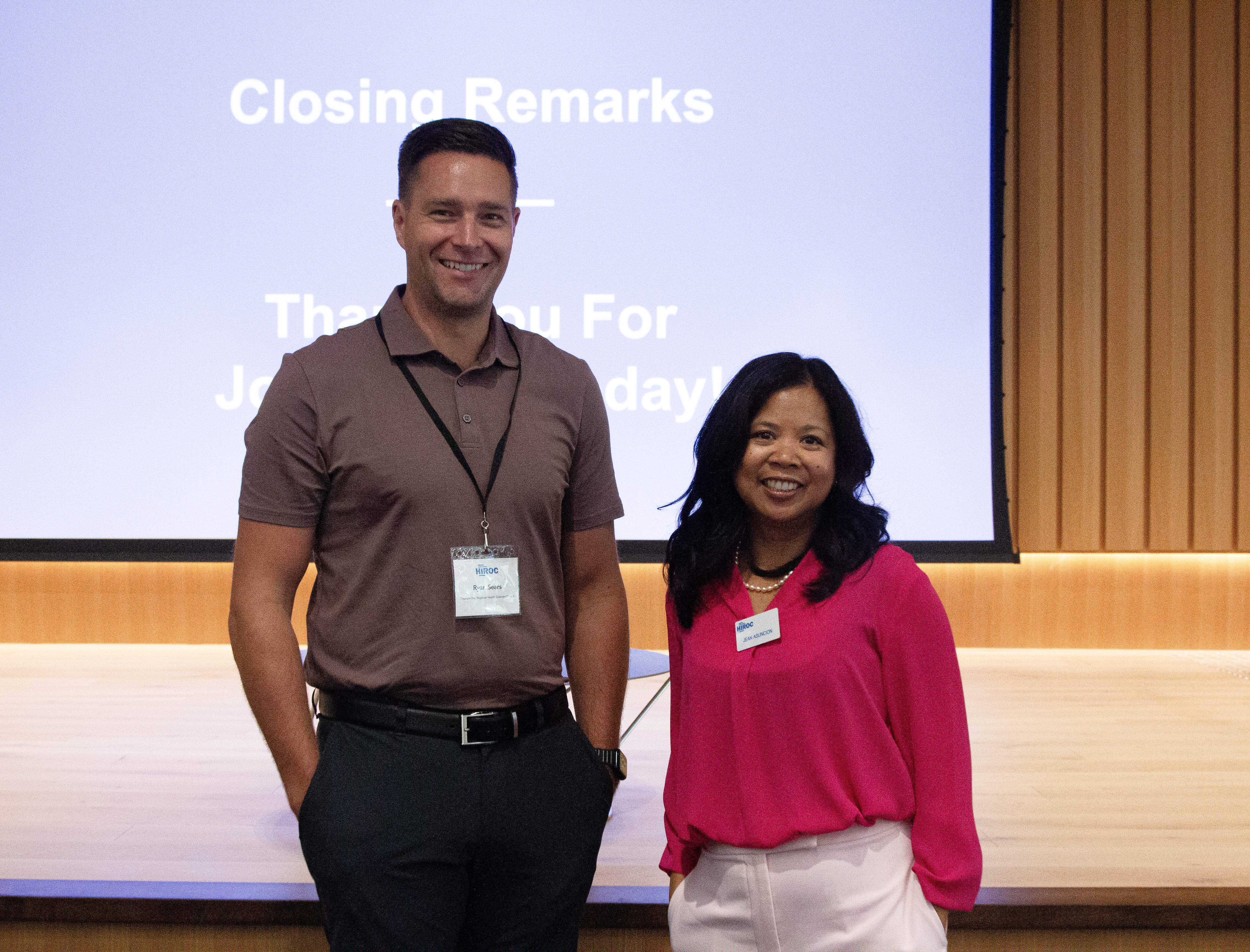 HIROC’s Jean Asuncion, right, poses with an attendee in front of the stage.