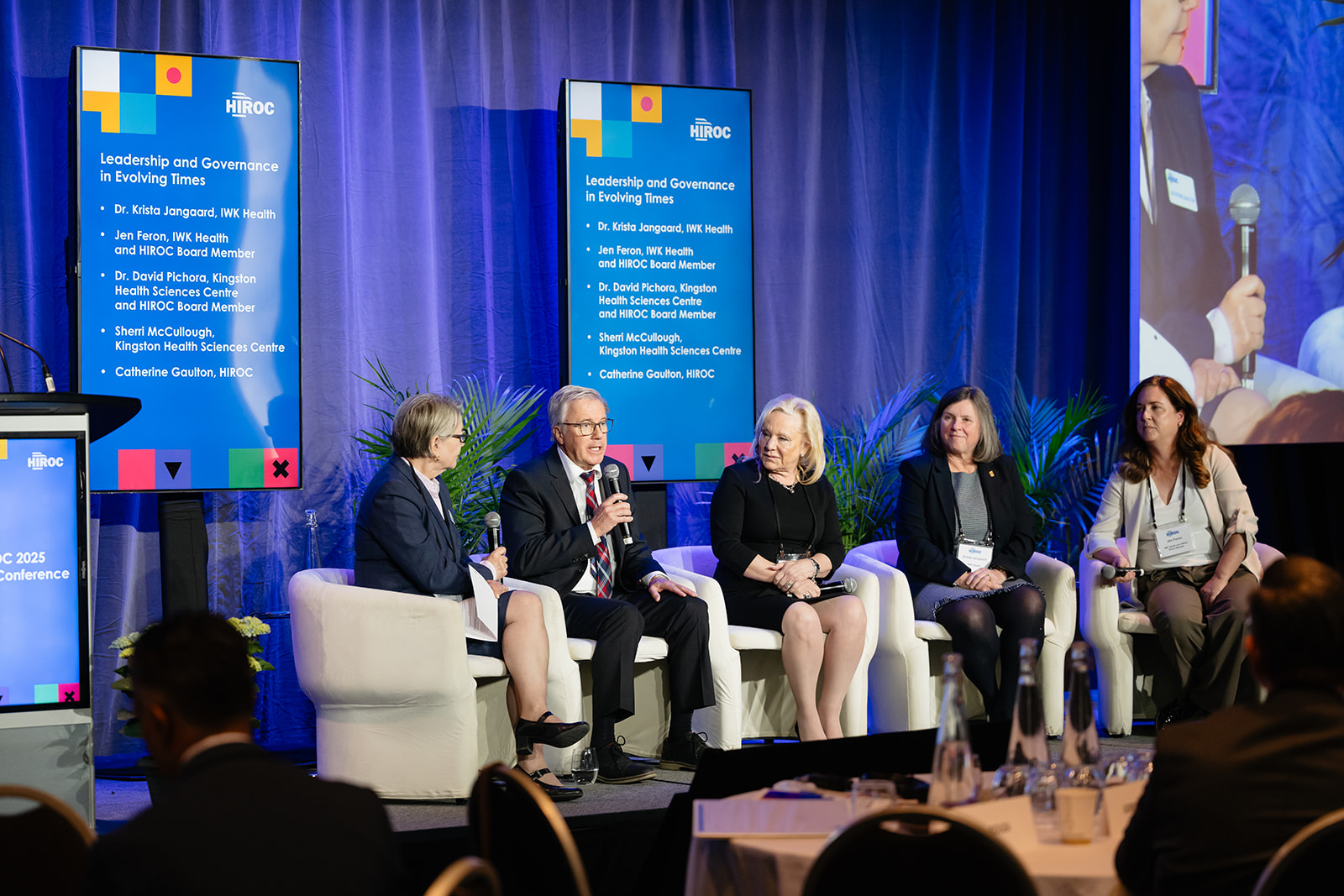 Leadership panel speakers seated in chairs on the conference stage.