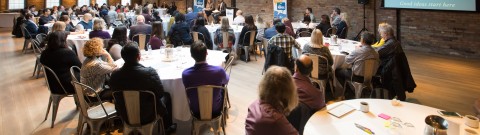 Wide shot of HIROC group at Cafe event, two people on podium