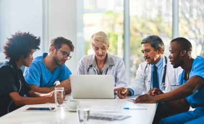 Healthcare professionals gather around a laptop