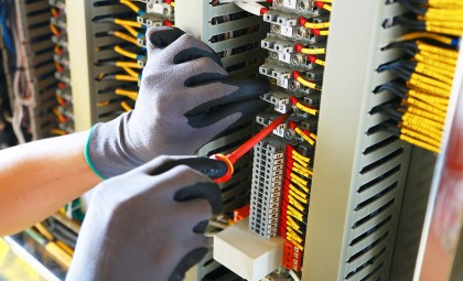 A close up photo of an electrician working on an electrical unit
