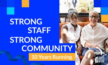 Image reading "strong staff, strong community, 10 years running" featuring photo of 2 employees sitting down and smiling at camera