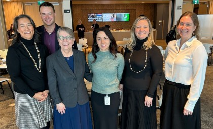Panel and hosts from the event standing together smiling