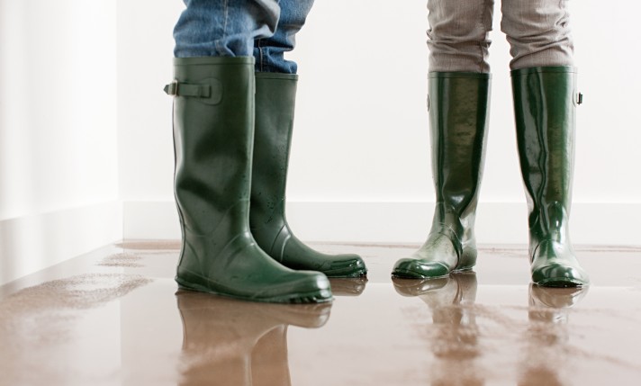 Image of two people standing on a wet floor in green rain boots,