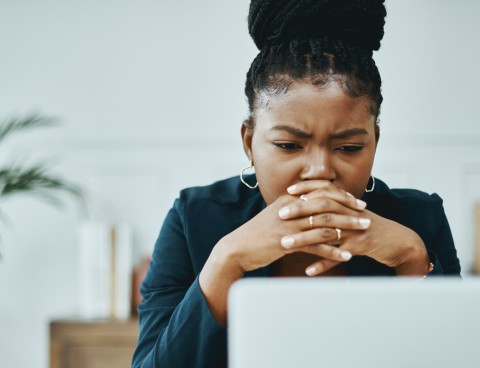Image of person looking worried over their laptop